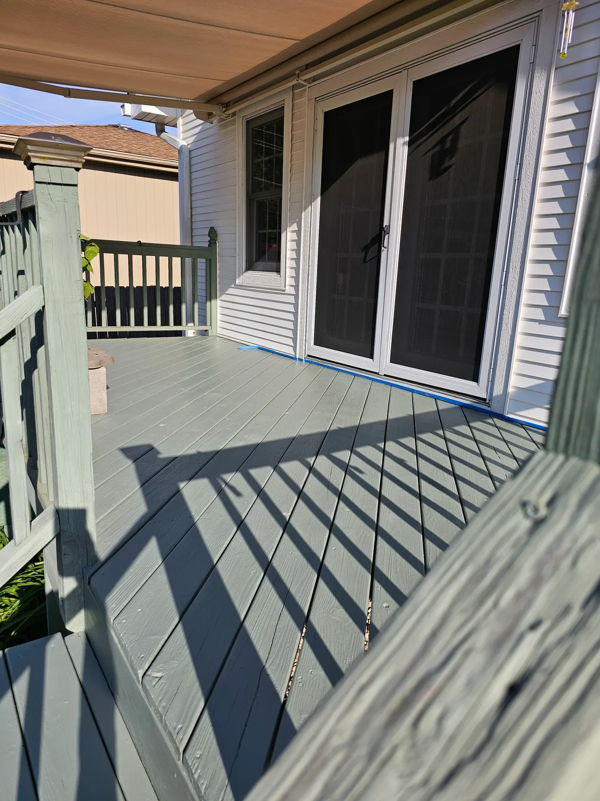 The same deck under an even coat of fresh green deck paint across the boards and railings.