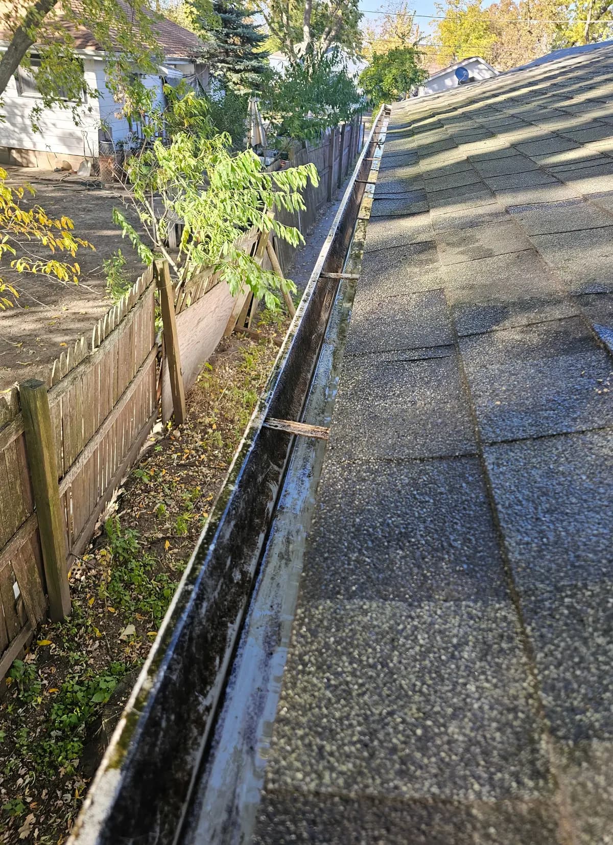 The same garage gutter run cleared out and rinsed, running clean along the edge of the roof.