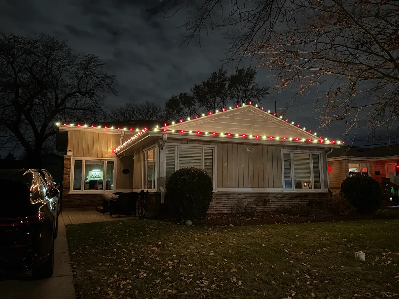 Home at night with alternating red and warm white bulbs outlining the roofline and front gable.